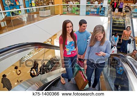 Stock Photograph - three teens at mall escalator. Fotosearch