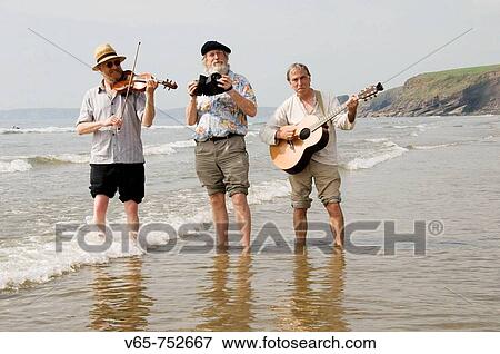 Three traditional acoustic folk musicians playing music on the beach and paddling in the sea at Druidston Haven, Pembrokeshire Coast National Park, WALES, UK View Large Photo Image Stock Photo - Three traditional acoustic folk musicians playing music on the beach and paddling in the sea at Druidston Haven, Pembrokeshire Coast National Park, WALES, UK. Fotosearch