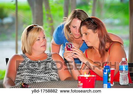 Three women share pictures on smartphone View Large Photo Image Stock Image - Three women share pictures on smartphone. Fotosearch