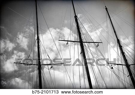 Three wooden masts of a classic sailboats with a background of sky with clouds View Large Photo Image Stock Image - Three wooden masts of a classic sailboats with a background of sky with clouds. Fotosearch