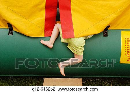 Stock Image - Three year old boy climbs out of play area. Fotosearch