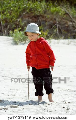 Three year old boy playing with a wooden stick on a sandy beach View Large Photo Image Stock Photo - Three year old boy playing with a wooden stick on a sandy beach. Fotosearch