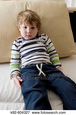 Three year old boy sitting on a couch. View Large Photo Image Stock Photo - Three year old boy sitting on a couch.. Fotosearch