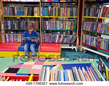 Three year old caucasian girl in preschool top looking at books in a public library. View Large Photo Image Stock Photo - Three year old caucasian girl in preschool top looking at books in a public library.. Fotosearch