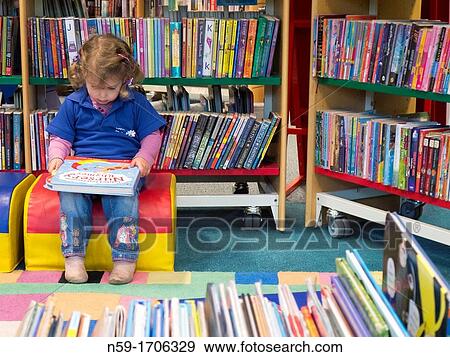 Three year old caucasian girl in preschool top looking at books in a public library. View Large Photo Image Stock Photo - Three year old caucasian girl in preschool top looking at books in a public library.. Fotosearch