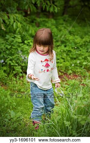 Stock Image - Three year old child exploring nature in Sheridan, Indiana, USA. Fotosearch