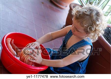 Stock Photo - Three year old girl bathing her doll, France.. Fotosearch