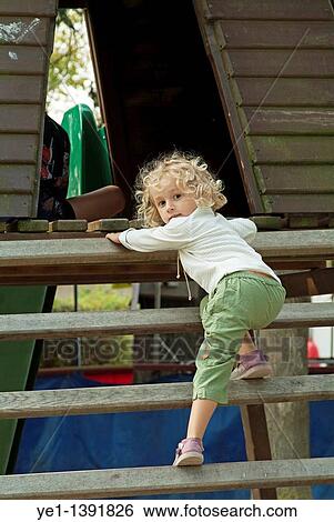 Three year old girl climbing wooden steps in the playground of a public park View Large Photo Image Stock Photograph - Three year old girl climbing wooden steps in the playground of a public park. Fotosearch