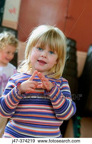 Three year old girl looking into camera, doing the actions to a nursrey rhyme View Large Photo Image Stock Photo - Three year old girl looking into camera, doing the actions to a nursrey rhyme. Fotosearch