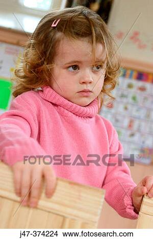 Three year old girl, looking very pensive and worried, at nursrey school View Large Photo Image Picture - Three year old girl, looking very pensive and worried, at nursrey school. Fotosearch