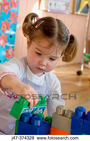 Three year old girl, playing with building bricks at nursrey school View Large Photo Image Stock Photo - Three year old girl, playing with building bricks at nursrey school. Fotosearch