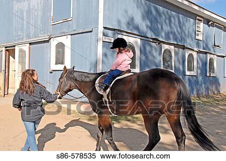 Three year old girl riding a horse; mother leading, at Stanhope Stables, Huntington, NY. View Large Photo Image Stock Photography - Three year old girl riding a horse; mother leading, at Stanhope Stables, Huntington, NY.. Fotosearch
