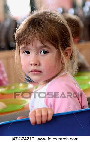 Three year old girl sitting at table leaning over the back of a chair looking serious View Large Photo Image Stock Image - Three year old girl sitting at table leaning over the back of a chair looking serious. Fotosearch