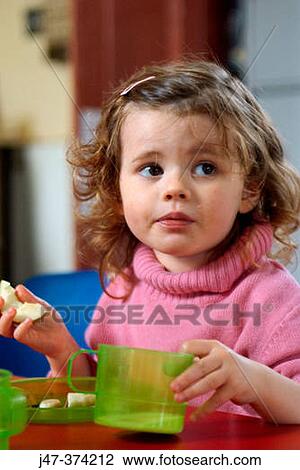 Three year old girl sitting at table drinking and eating fruit View Large Photo Image Stock Image - Three year old girl sitting at table drinking and eating fruit. Fotosearch