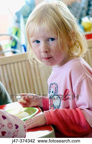Three year old girl sitting at table eating fruit View Large Photo Image Stock Image - Three year old girl sitting at table eating fruit. Fotosearch
