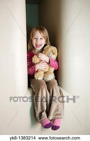 Picture - Three Year Old Girl Sitting in Stove Recess With Teddy Bear. Fotosearch