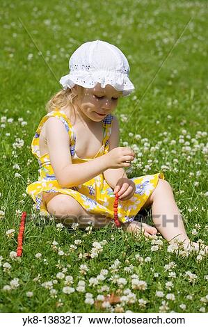 Stock Photo - Three Year Old Girl Sitting on Grass, Strawberries on a Grasstraw. Fotosearch