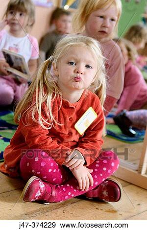 Three year old girl sitting on the floor at nursrey school, blowing a kiss into camera View Large Photo Image Stock Photo - Three year old girl sitting on the floor at nursrey school, blowing a kiss into camera. Fotosearch