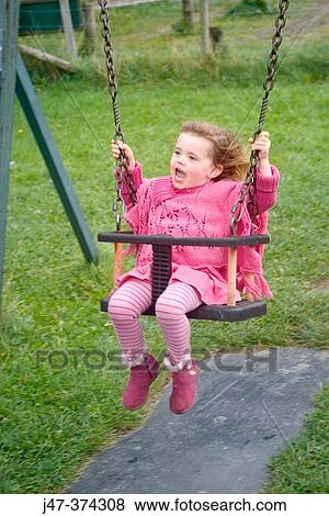 Three year old girl swinging in the park all dressed in pink laughing View Large Photo Image Stock Photo - Three year old girl swinging in the park all dressed in pink laughing. Fotosearch