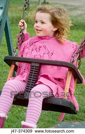 Three year old girl swinging in the park all dressed in pink View Large Photo Image Stock Photo - Three year old girl swinging in the park all dressed in pink. Fotosearch