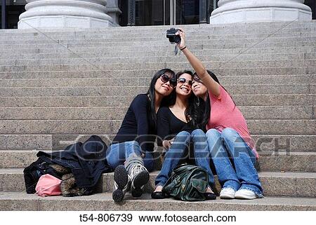 Three young Asian Girls sitting on the Stairs from the Mainpostoffice and make a Foto View Large Photo Image Stock Photo - Three young Asian Girls sitting on the Stairs from the Mainpostoffice and make a Foto. Fotosearch