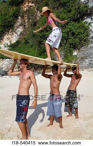 Stock Photography - three young men lifting girl with surfboard. Fotosearch