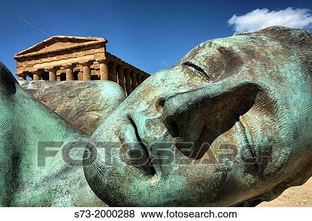 Stock Photo - Throw down bronze statue and antique Temple of Concordia in Valley of the Temples, Agrigento, Sicily, Italy. Fotosearch