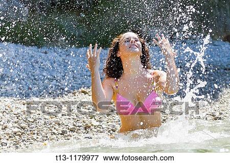 Throwing water upwards young woman standing in the shallow sea View Large Photo Image Stock Photo - Throwing water upwards young woman standing in the shallow sea. Fotosearch