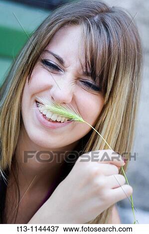 Stock Photo - Tickling with a blade of grass young woman portrait. Fotosearch