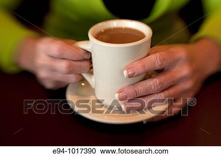 tight view of a woman's hands on a white coffee cup on a saucer on a table in a restaurant View Large Photo Image Stock Image - tight view of a woman's hands on a white coffee cup on a saucer on a table in a restaurant. Fotosearch