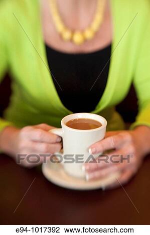 tight view of a woman's hands on a white coffee cup on a saucer on a table in a restaurant View Large Photo Image Stock Image - tight view of a woman's hands on a white coffee cup on a saucer on a table in a restaurant. Fotosearch