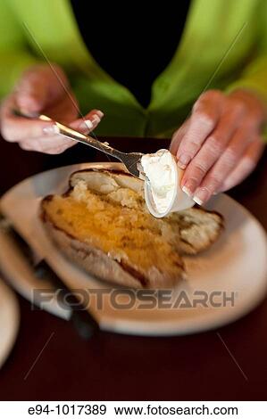 tight view of a woman's hands putting butter and sour cream on a baked potato in a restaurant View Large Photo Image Stock Photo - tight view of a woman's hands putting butter and sour cream on a baked potato in a restaurant. Fotosearch