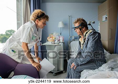 Tilburg, Netherlands. Physio therapist instructing a post operative patient with fractured cervical on how to walk again, after a head brace is mounted. View Large Photo Image Stock Photo - Tilburg, Netherlands. Physio therapist instructing a post operative patient with fractured cervical on how to walk again, after a head brace is mounted.. Fotosearch