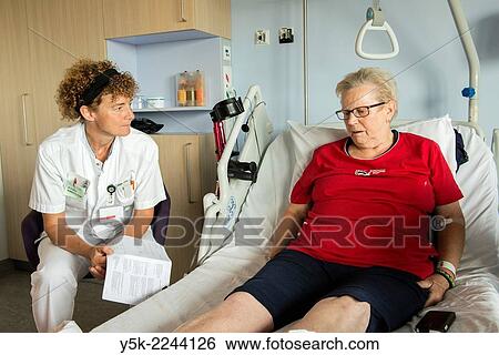 Stock Photograph - Tilburg, Netherlands. Physio therapist instructing a female post operative patient on how to walk again, after reviving a new hip in surgery.. Fotosearch