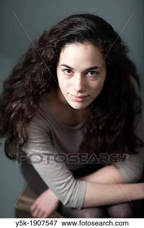Tilburg, Netherlands Portrait of a young brunette against a grey background, sitting on a stool View Large Photo Image Stock Photo - Tilburg, Netherlands Portrait of a young brunette against a grey background, sitting on a stool. Fotosearch