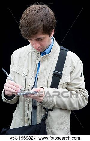 Tilburg, Netherlands. Portrait of a young intellectual male, writing down notes on his vintage notepad during a portrait session on the weekly market. View Large Photo Image Stock Photo - Tilburg, Netherlands. Portrait of a young intellectual male, writing down notes on his vintage notepad during a portrait session on the weekly market.. Fotosearch