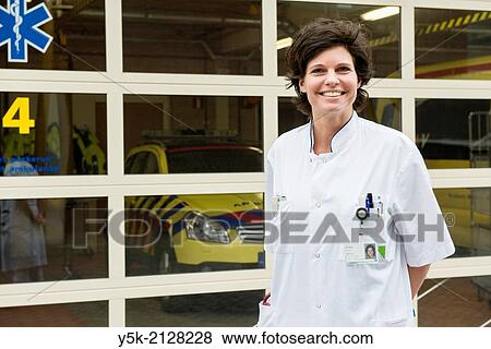 Stock Photo - Tilburg, Netherlands. Portrait of the trauma and a hospitals first aid doctor, Mrs. Linda D, in front of the ambulances garage, just opposite the first aid ward of a regional hospital.. Fotosearch