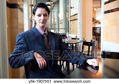 Stock Image - Tilburg, Netherlands Young woman, dressed up as a businessman, having lunch in a grand-cafe. Fotosearch