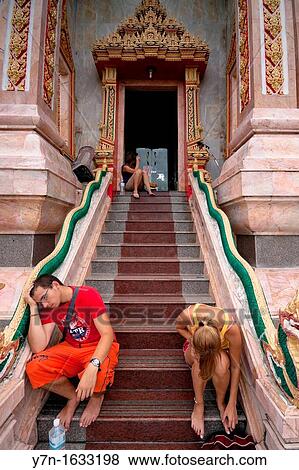 Tired European tourists resting at entrance to Wat Chalong - Buddhist temple in Phuket, Thailand Wat Chalong is the largest and the most visited of Phuket's temples View Large Photo Image Stock Photo - Tired European tourists resting at entrance to Wat Chalong - Buddhist temple in Phuket, Thailand Wat Chalong is the largest and the most visited of Phuket's temples. Fotosearch