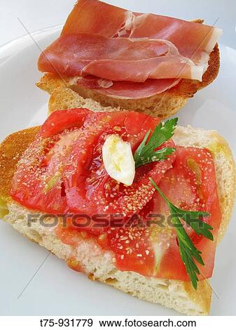 Stock Photo - Toasted bread with tomato, olive oil, garlic, parsley and ham. Fotosearch