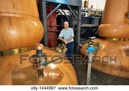 Tobermory Whisky Distillery, Isle of Mull Scotland Still man Ruairaidh Currie Traditional copper pot stills in the Still Room View Large Photo Image Stock Photo - Tobermory Whisky Distillery, Isle of Mull Scotland Still man Ruairaidh Currie Traditional copper pot stills in the Still Room. Fotosearch