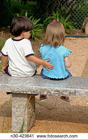Toddler boy and girl sitting on park bench View Large Photo Image Stock Image - Toddler boy and girl sitting on park bench. Fotosearch