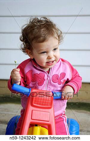 Toddler girl playing on a plastic tricycle. View Large Photo Image Stock Image - Toddler girl playing on a plastic tricycle.. Fotosearch