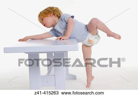 Stock Image - Toddler hanging over a bench. Fotosearch