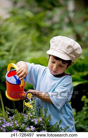 Toddler is watering plants in the garden View Large Photo Image Stock Photo - Toddler is watering plants in the garden. Fotosearch