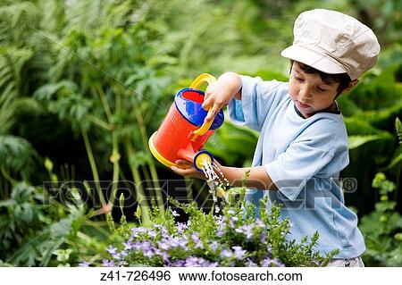 Toddler is watering plants in the garden View Large Photo Image Stock Photograph - Toddler is watering plants in the garden. Fotosearch