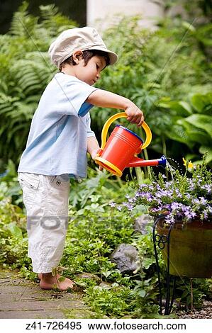 Toddler is watering plants in the garden View Large Photo Image Stock Photography - Toddler is watering plants in the garden. Fotosearch