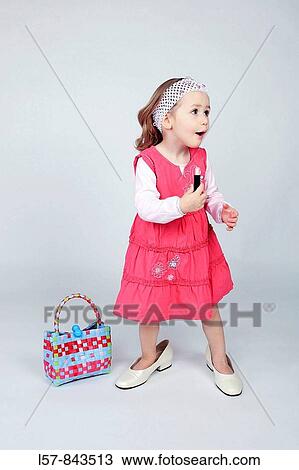 toddler, little girl, wearing pink dress and grown up dress shoes, standing next to handbag, holding lipstick, white background, studio, Switzerland View Large Photo Image Stock Image - toddler, little girl, wearing pink dress and grown up dress shoes, standing next to handbag, holding lipstick, white background, studio, Switzerland. Fotosearch