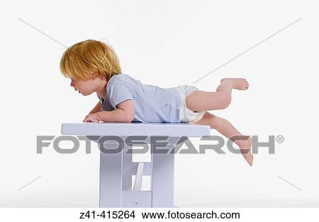 Picture - Toddler lying over a bench. Fotosearch