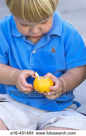 Stock Image - toddler peeling tangerine. Fotosearch